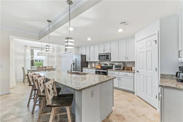 a kitchen with kitchen island granite countertop a table chairs microwave and refrigerator