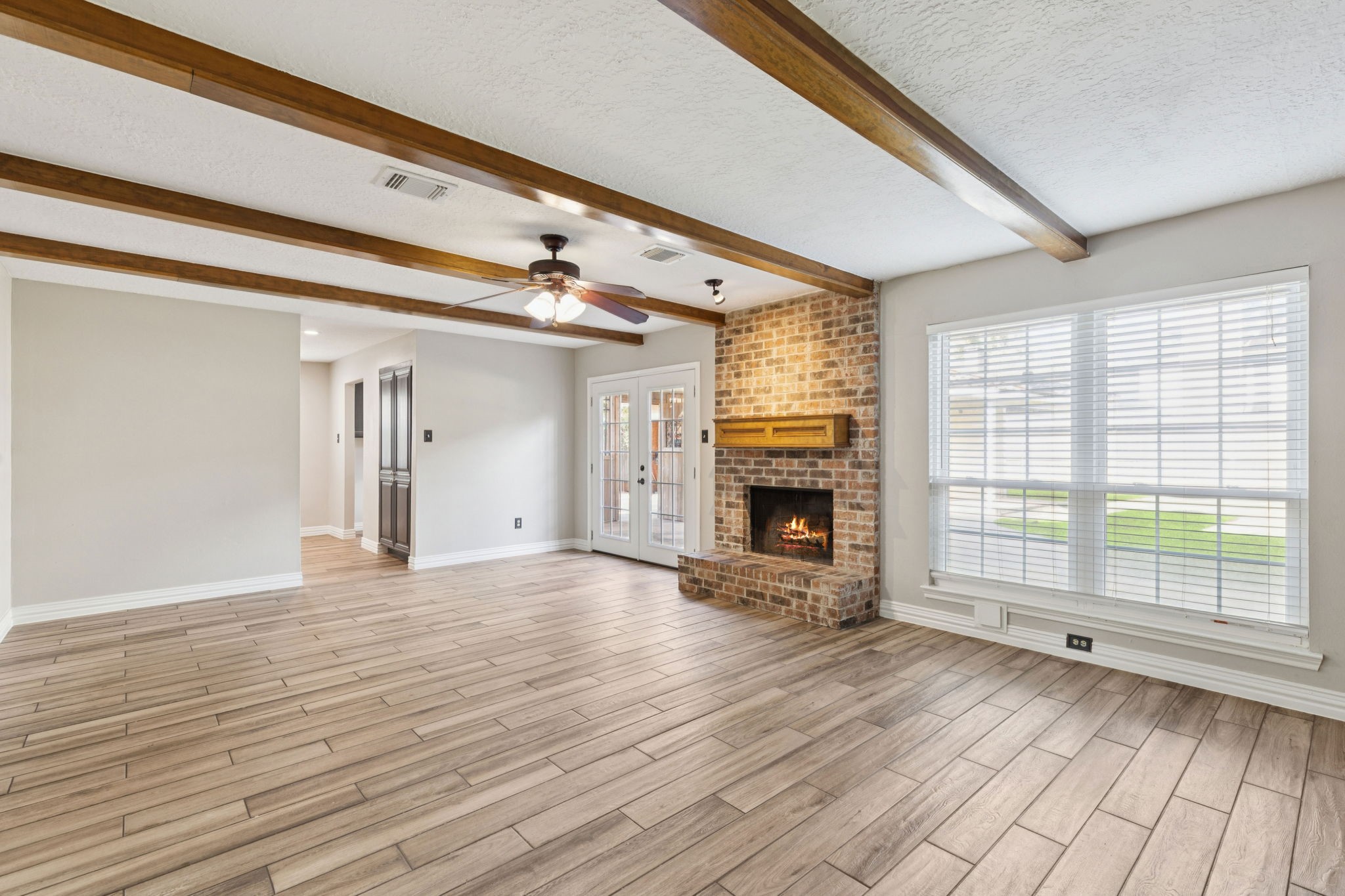 3630 Chapel Square Drive Spring, TX 77388 - Photo 16 of 24 Discover the heart of the home in this living area where fresh paint, high ceilings, exposed wood beams, and a striking brick fireplace come together to create a warm and inviting gathering space.