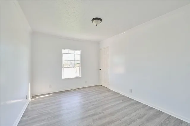 a view of an empty room with wooden floor and window