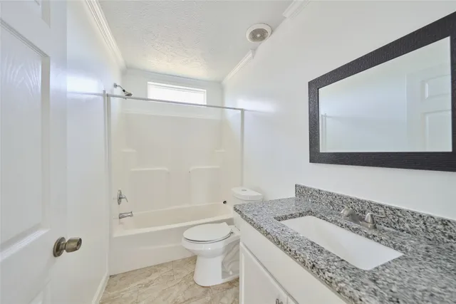 a bathroom with a granite countertop sink mirror vanity and toilet