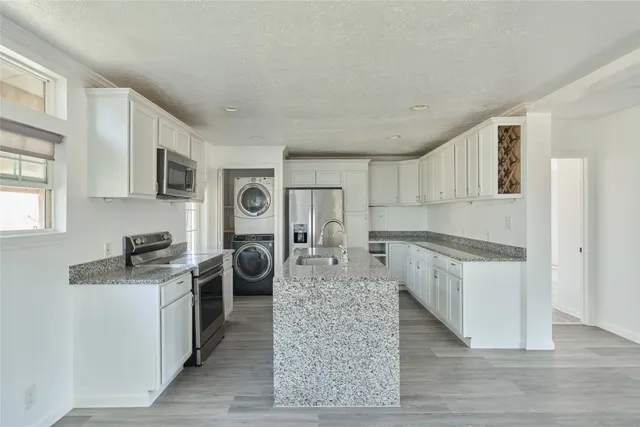 a kitchen with granite countertop a refrigerator stove top oven and sink