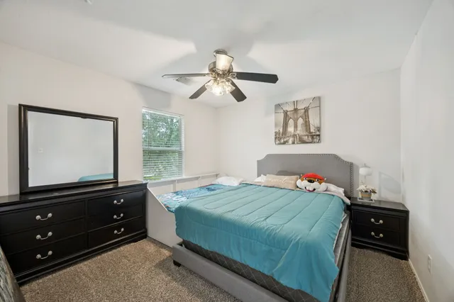 a bedroom with a bed and a flat tv screen on dresser