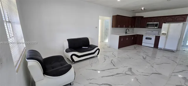 a kitchen with stainless steel appliances kitchen island granite countertop a refrigerator a stove a sink dishwasher and a chairs with wooden floor