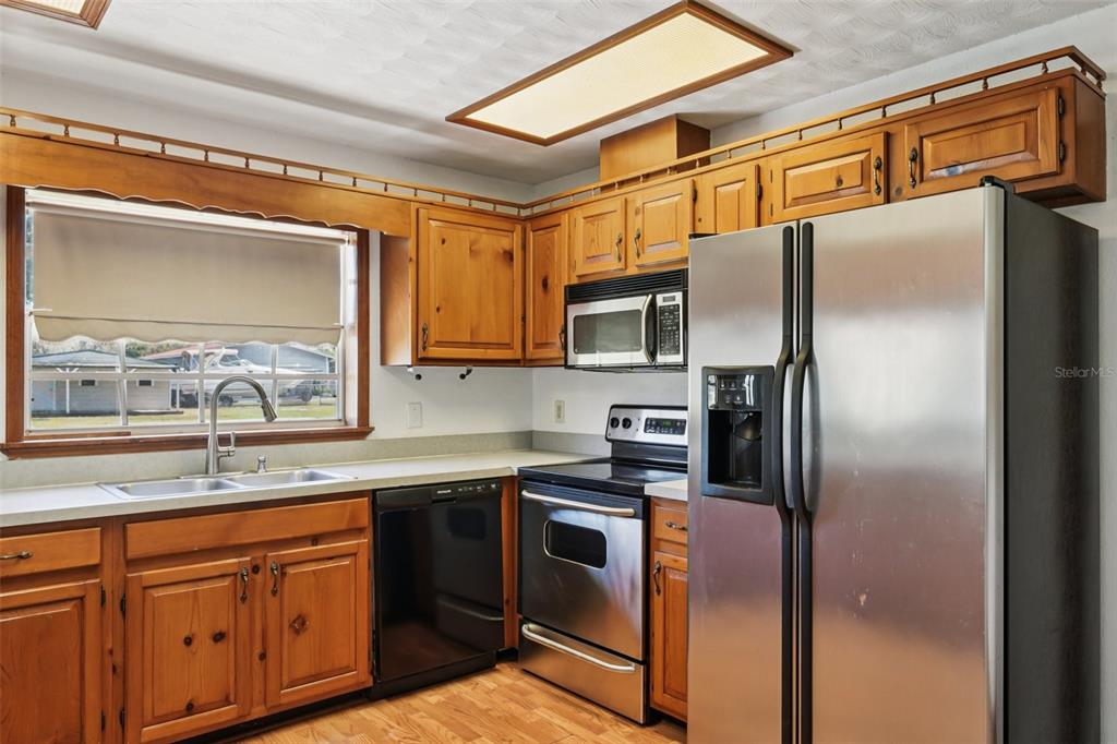 4716 Gallagher Road Plant City, FL 33565 - Photo 29 of 69 a kitchen with stainless steel appliances granite countertop a refrigerator a stove a sink and dishwasher with wooden floor