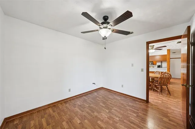 a view of empty room with wooden floor and ceiling fan