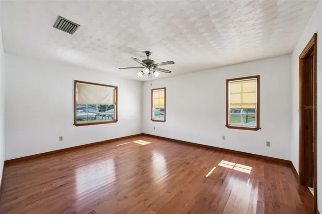 an empty room with a window and ceiling fan