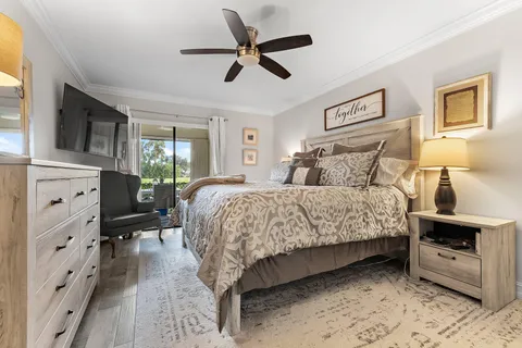 a bedroom with a bed a couch and a flat tv screen on dresser