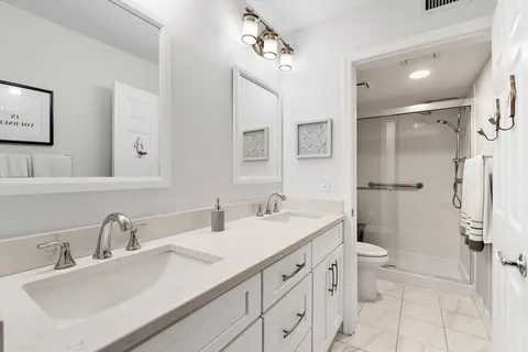 a bathroom with a double vanity sink toilet and a mirror