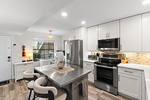 a kitchen with stainless steel appliances a stove a sink a microwave a refrigerator and white cabinets