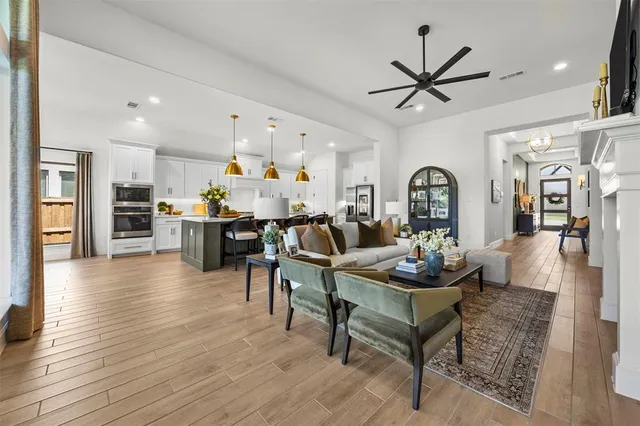 a living room with furniture kitchen view and a wooden floor