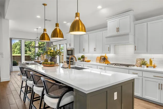 a kitchen with stainless steel appliances granite countertop a sink a stove and a wooden floors