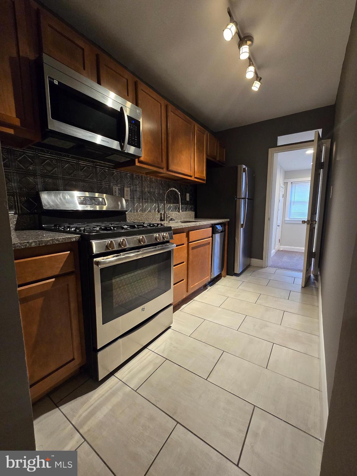4044 7th Street Northeast, Unit 2 Washington, DC 20017 - Photo 2 of 8 a kitchen with stainless steel appliances granite countertop a stove a microwave and a sink