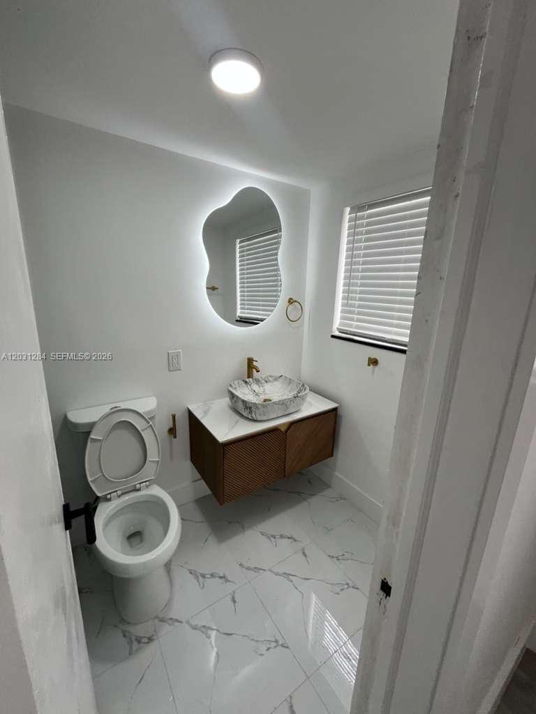 316 Surfside Boulevard, Unit 2 Surfside, FL 33154 - Photo 5 of 13 a bathroom with a toilet a sink and mirror
