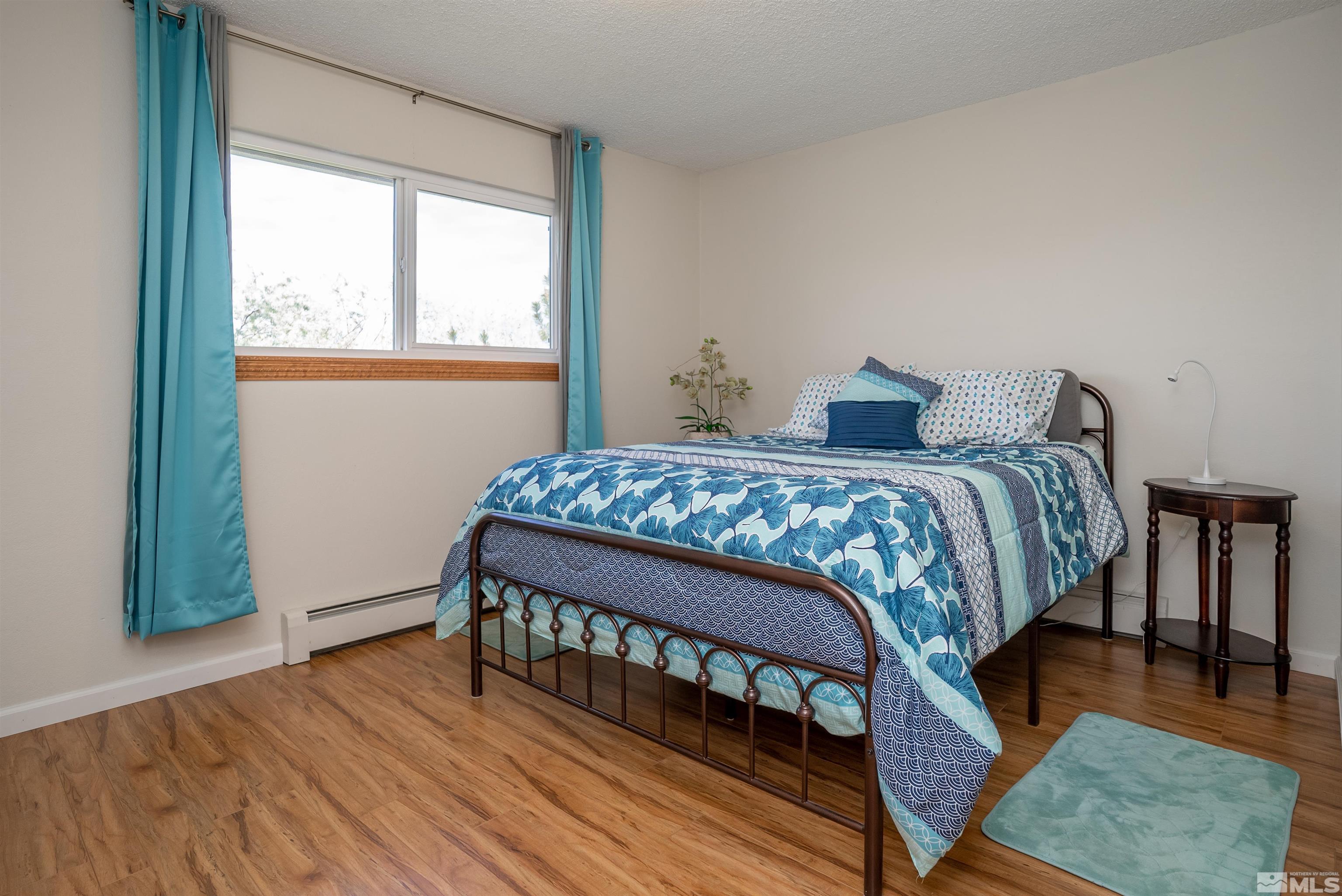 4936 Koenig Road Reno, NV 89506 - Photo 14 of 30 a bedroom with a bed a table and wooden floor