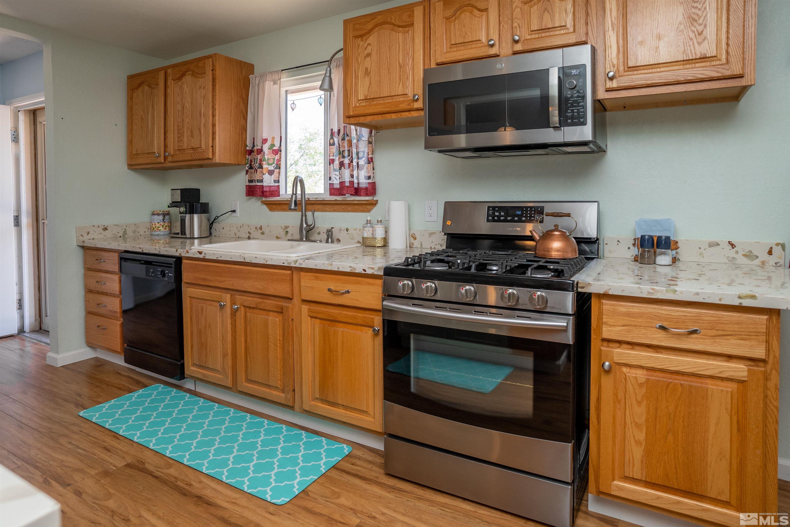 4936 Koenig Road Reno, NV 89506 - Photo 6 of 30 a kitchen with stainless steel appliances granite countertop a stove a microwave a sink and cabinets