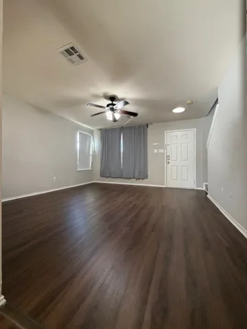 a view of an empty room with wooden floor and a window