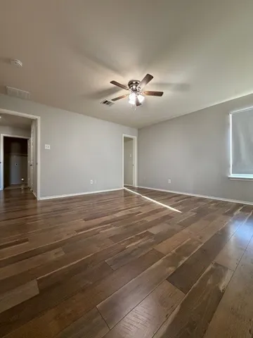 a view of empty room with wooden floor and fan