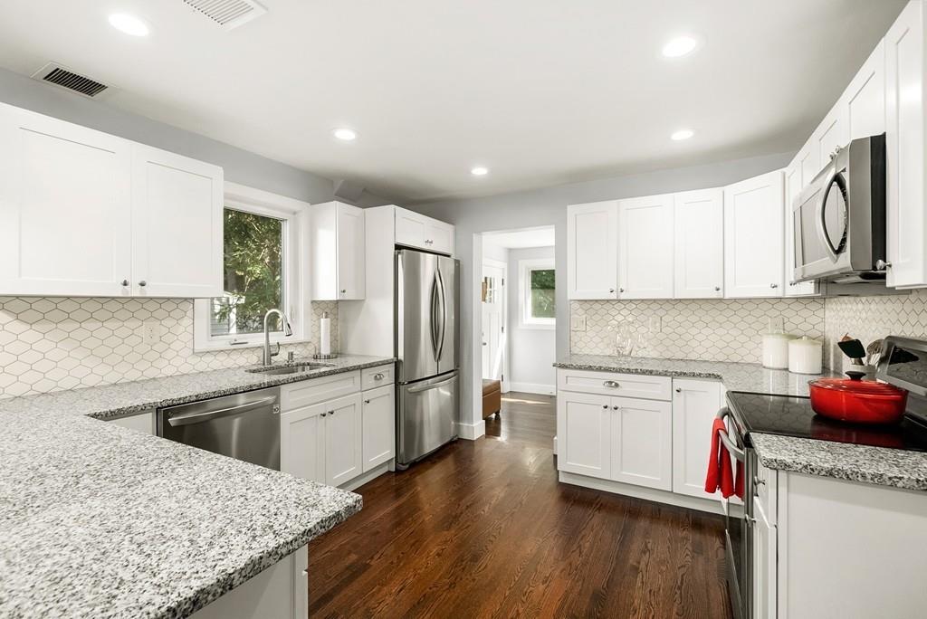 a kitchen with granite countertop a sink stove refrigerator and cabinets