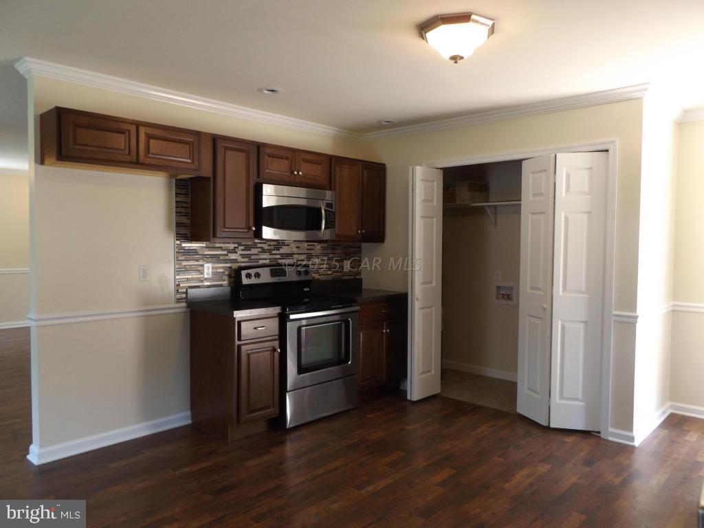27100 Mt Vernon Road Princess Anne, MD 21853 - Photo 9 of 22 a kitchen with a refrigerator stove and wooden cabinets