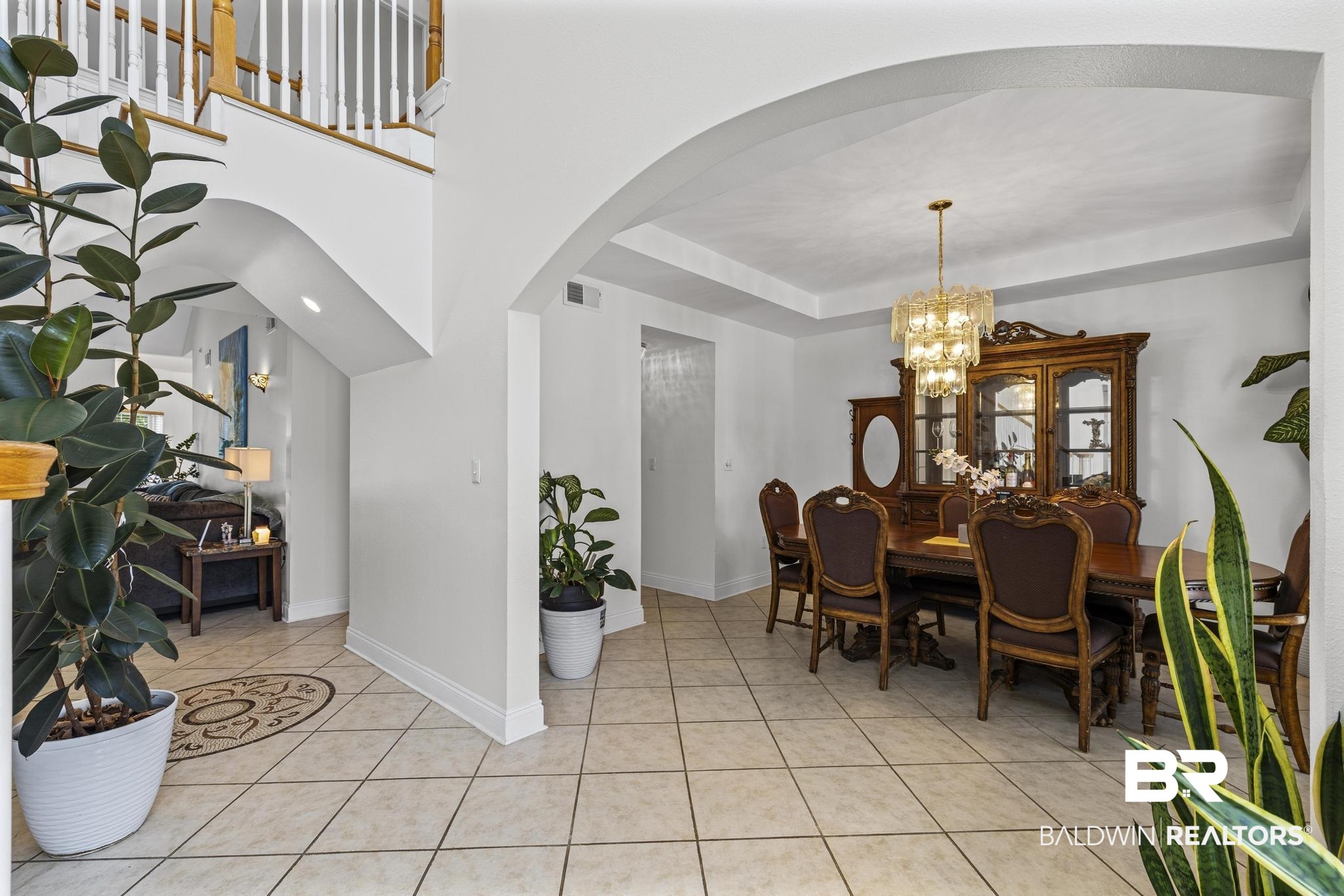 32875 Faircloth Road Lillian, AL 36549 - Photo 18 of 85 Dining area with arched walkways, a raised ceiling, hanging lights, and light tile patterned floors