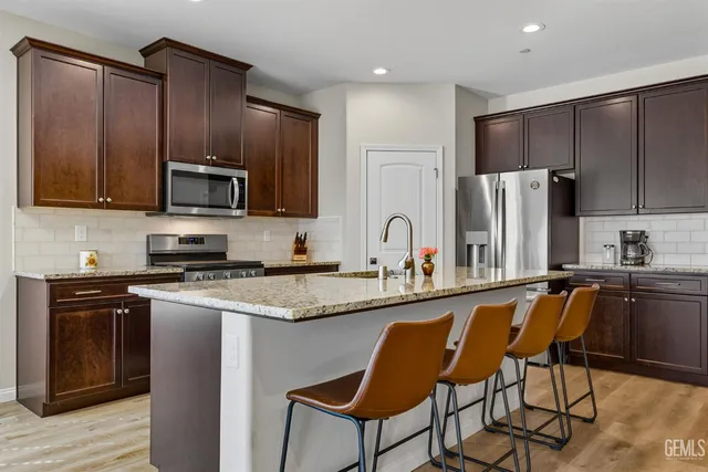 a kitchen with stainless steel appliances granite countertop a stove a sink dishwasher a refrigerator and a microwave