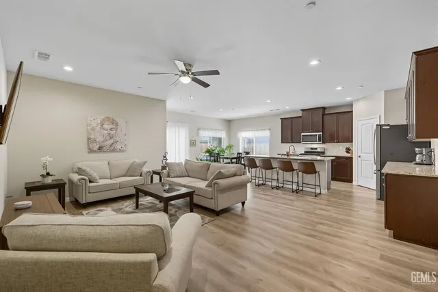a living room with furniture kitchen view and a wooden floor