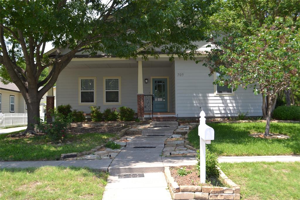 Inviting front view of the home with a large shade tree and neat landscaping.
