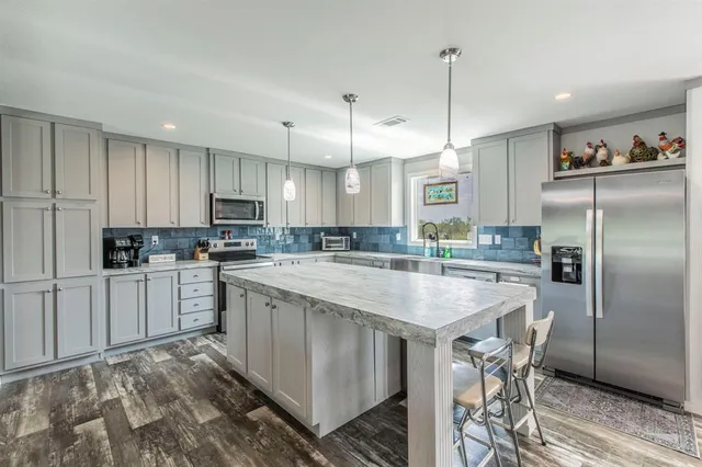 a kitchen with granite countertop a center island a sink cabinets and stainless steel appliances