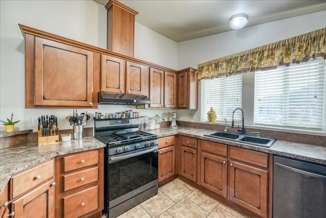 a kitchen with stainless steel appliances granite countertop a sink stove cabinets and a window