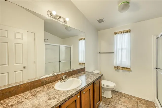 a bathroom with a granite countertop sink a mirror and a toilet
