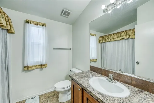 a bathroom with a granite countertop sink toilet and a mirror