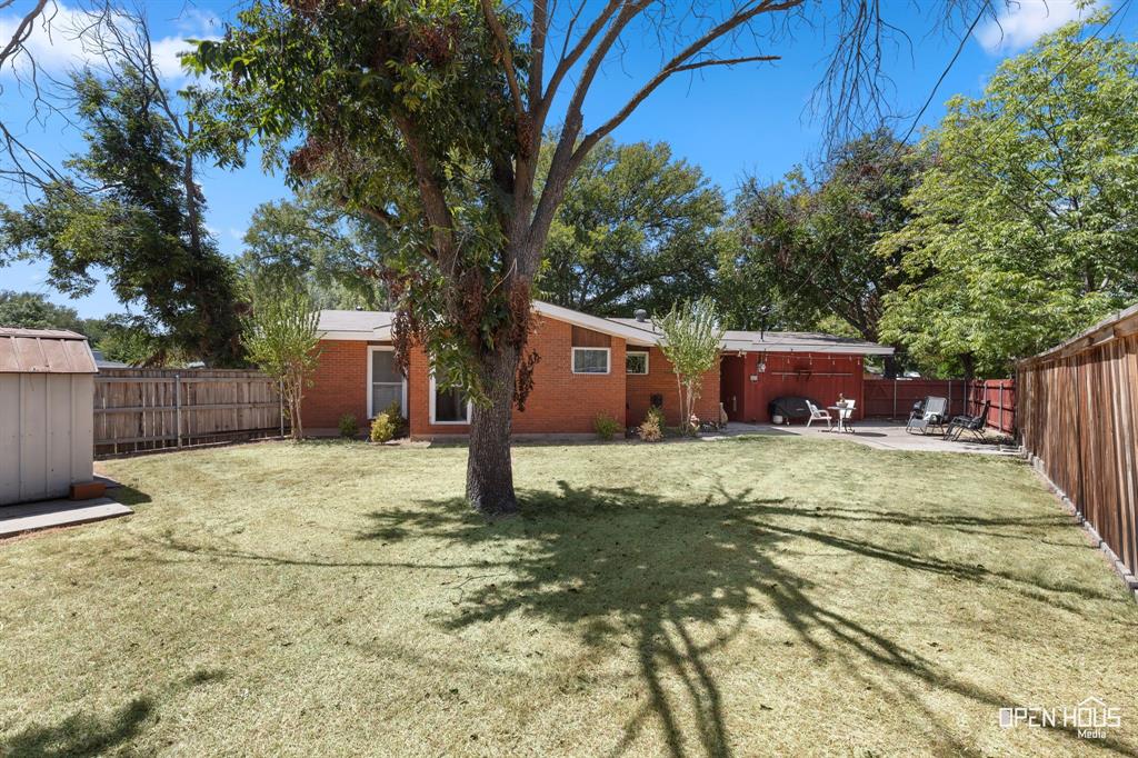 4419 Randel Drive Wichita Falls, TX 76308 - Photo 24 of 32 Expansive grassy yard with a privacy fence, mature trees, and a concrete patio