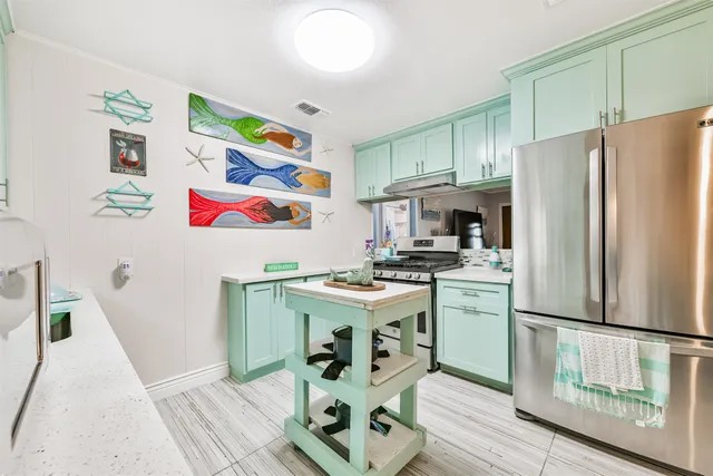 a kitchen with stainless steel appliances granite countertop a refrigerator a stove and a sink