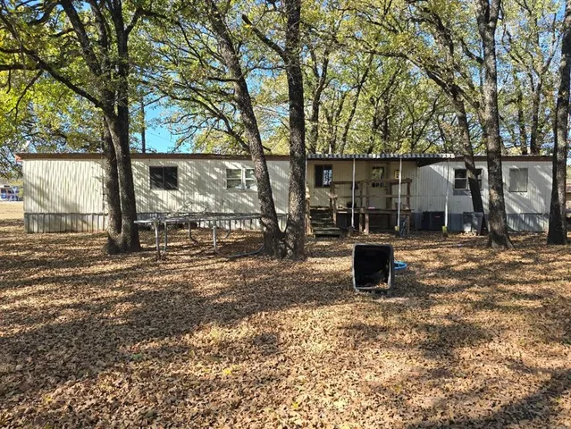 a view of a backyard with wooden fence and large trees