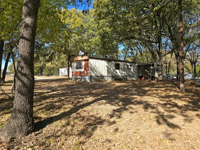 a backyard of a house with large trees and outdoor seating