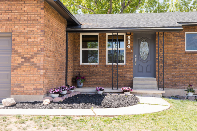 634 South 2100th Street West Vernal, UT 84078 - Photo 2 of 71 Brick exterior featuring a gray entry door with decorative glass, white-framed windows, and a covered porch