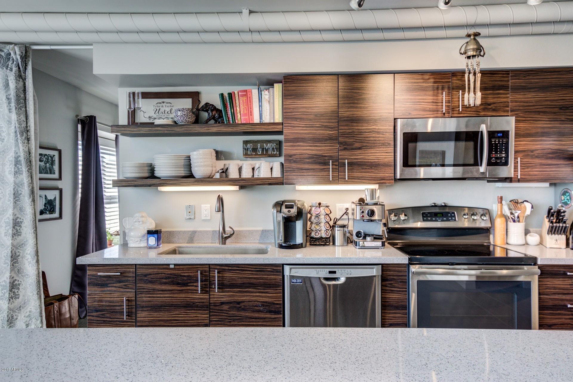 535 West Thomas Road, Unit 208 Phoenix, AZ 85013 - Photo 6 of 22 a kitchen with kitchen island granite countertop stainless steel appliances and wooden cabinets