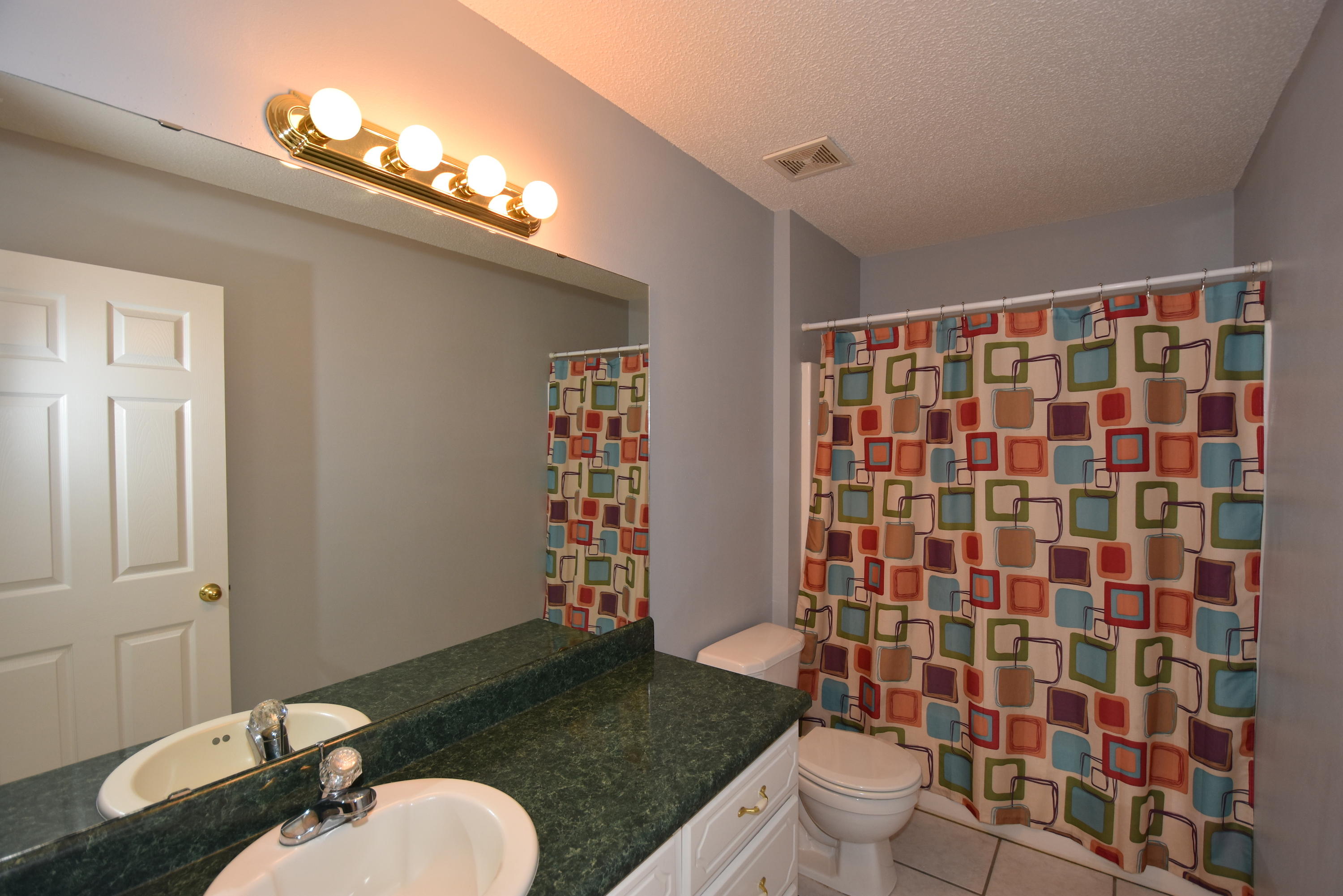 5817 Dairy Road Baker, FL 32531 - Photo 25 of 36 a bathroom with a granite countertop sink a toilet a mirror and shower curtain