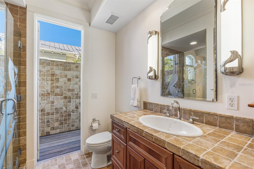 1601 Jean Lafitte Drive Boca Grande, FL 33921 - Photo 27 of 54 a bathroom with a granite countertop sink a toilet a mirror and shower