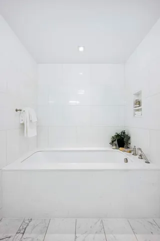 a bathroom with a tub sink and mirror
