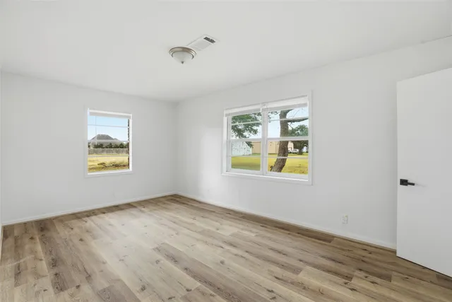 a view of an empty room with window and wooden floor