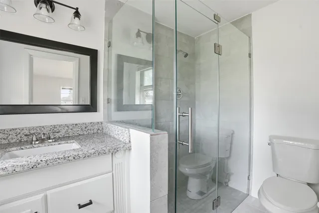 a bathroom with a granite countertop toilet a sink and a mirror