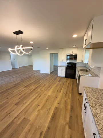 a large room with kitchen island stainless steel appliances wooden floor and stove