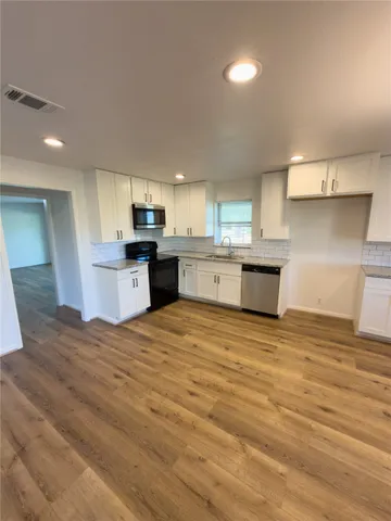 a large kitchen with stainless steel appliances granite countertop a stove and a sink