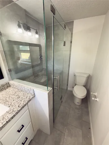a bathroom with a granite countertop sink a toilet and shower