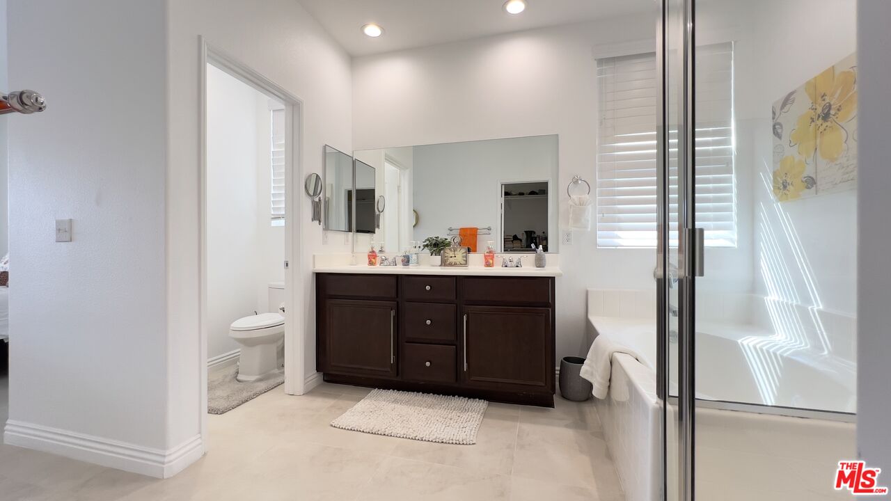 84330 Tramonto Way Indio, CA 92203 - Photo 10 of 18 a bathroom with a vanity a sink a mirror and a shower