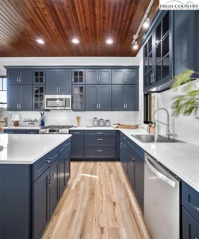 a kitchen with stainless steel appliances granite countertop a sink dishwasher a refrigerator and wooden floor