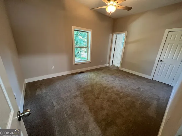 an empty room with windows and fan