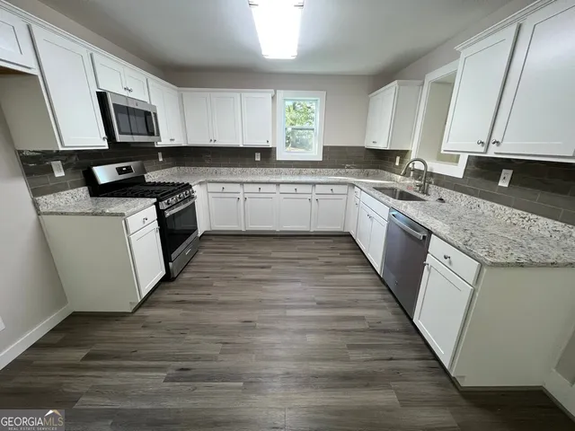 a kitchen with granite countertop wooden floors a sink and appliances
