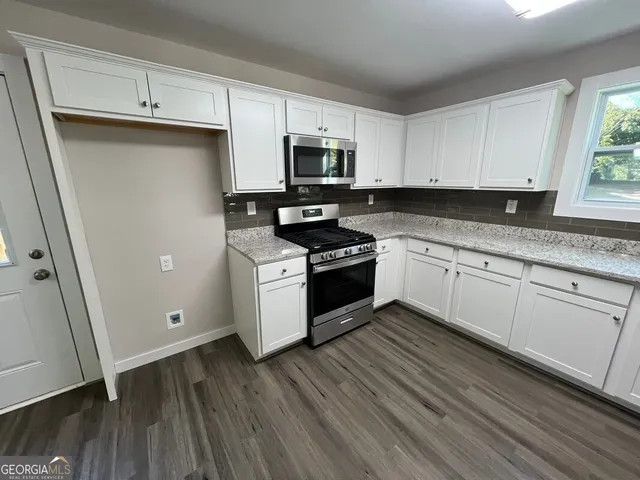a kitchen with granite countertop white cabinets and white appliances